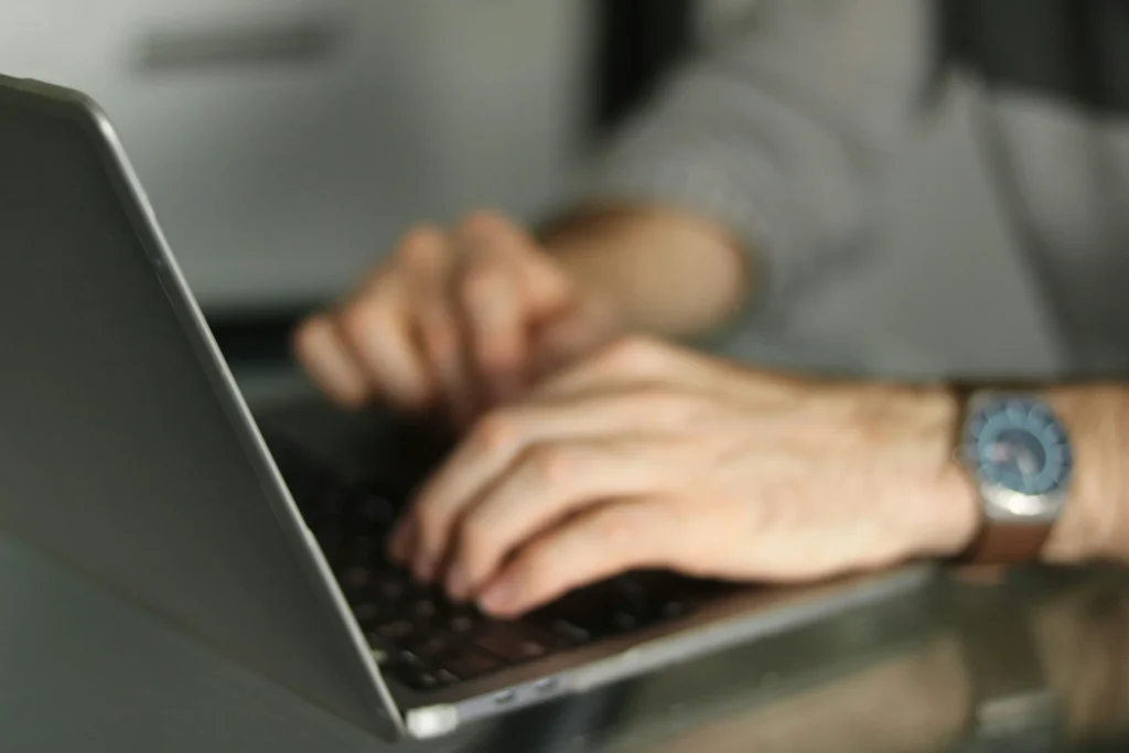 Nahaufnahme einer Person, die am Laptop eine Eingabe durchführt